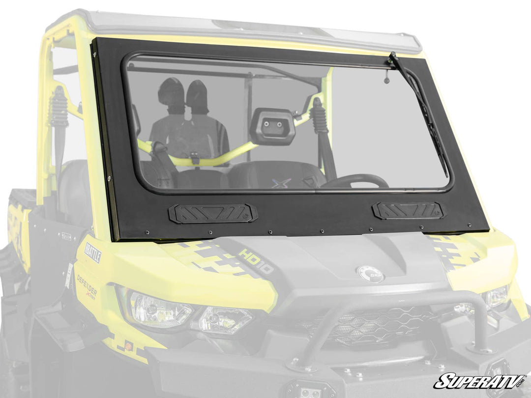 SuperATV Can-Am Defender Glass Windshield installed on a yellow utility vehicle, featuring a manual wiper and glare-reducing tint.