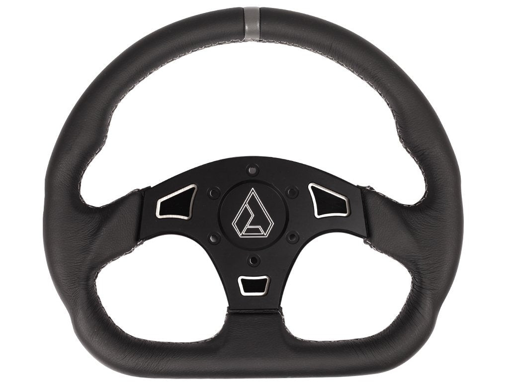 Black leather steering wheel with a 'D' shape design, featuring cut-out sections on a matte black central plate with a prominent Assault Industries logo. The steering wheel has a grey leather strip at the top and sporty grips on the sides.