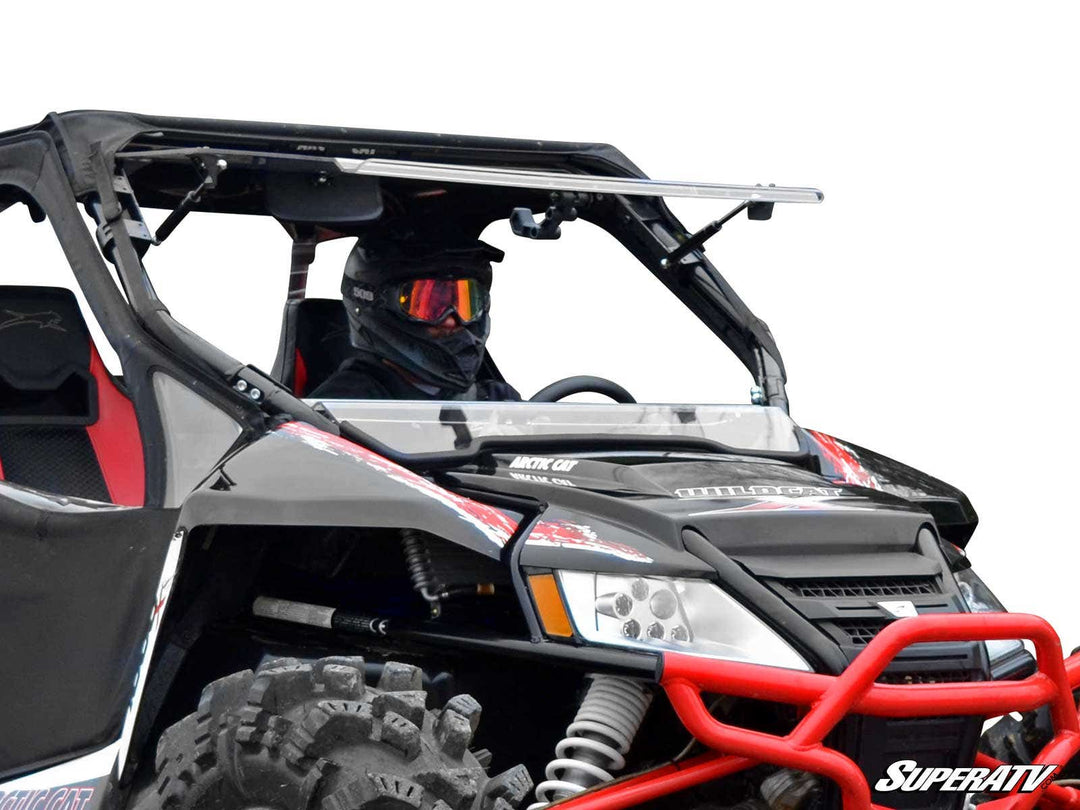 Arctic Cat Wildcat UTV equipped with a versatile, scratch-resistant flip windshield, showcasing its robust design and clear visibility. The vehicle is enhanced with a protective red frame and rugged tires, ready for challenging terrains.
