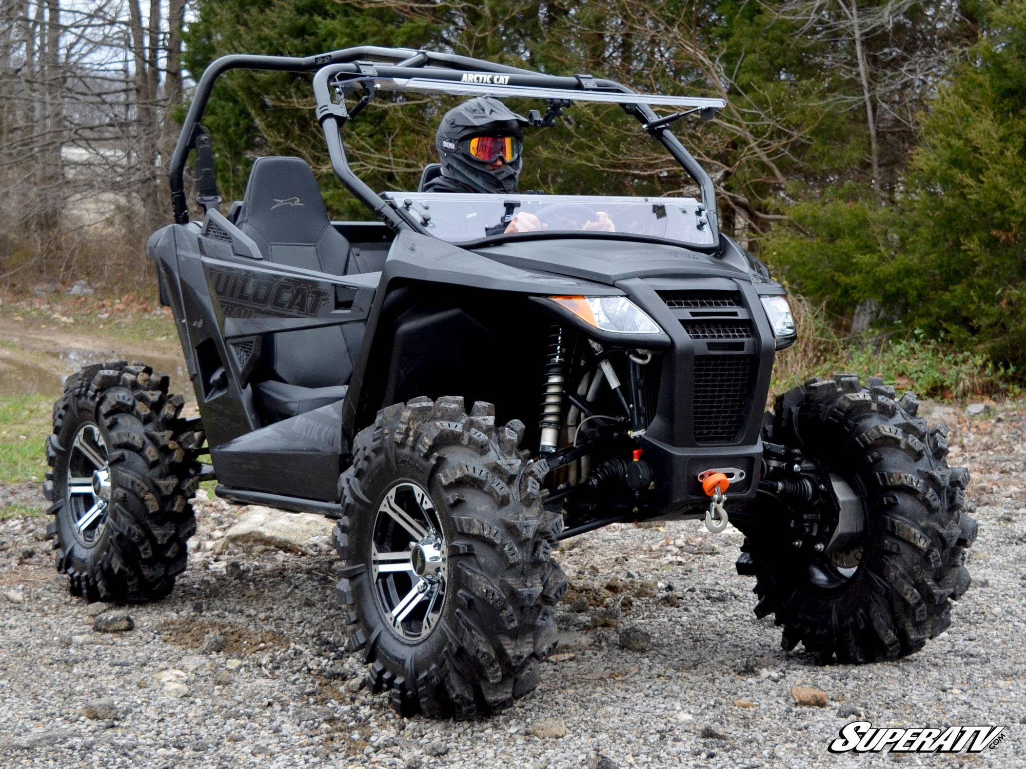 Arctic Cat Wildcat Trail Sport UTV parked outdoors, featuring aggressive tread tires and a visible flip windshield, in a rugged off-road setting.