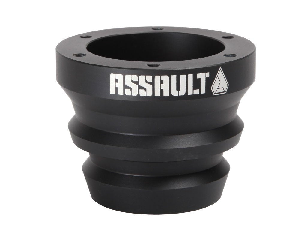 Black anodized Assault Industries steering wheel hub with bold 'ASSAULT' branding and a tapered design, featuring multiple screw holes for mounting.