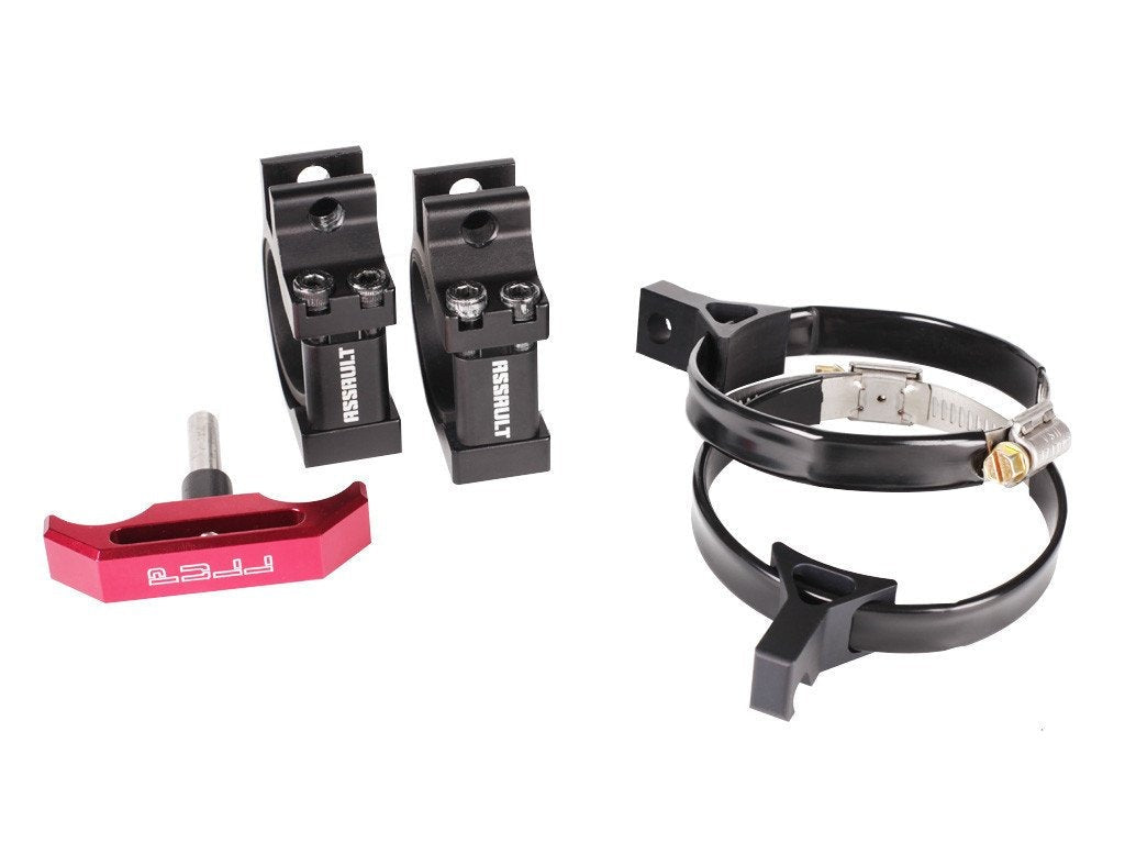 A set of robust, precision-engineered quick-release clamps from Assault Industries, displayed against a white background. The kit includes two black anodized aluminum clamps with mounting brackets, a silver metal band clamp, and a red quick-release pull handle. The items are designed to offer secure, adjustable mounting for accessories on off-road vehicles, showcasing industrial strength and sleek design.